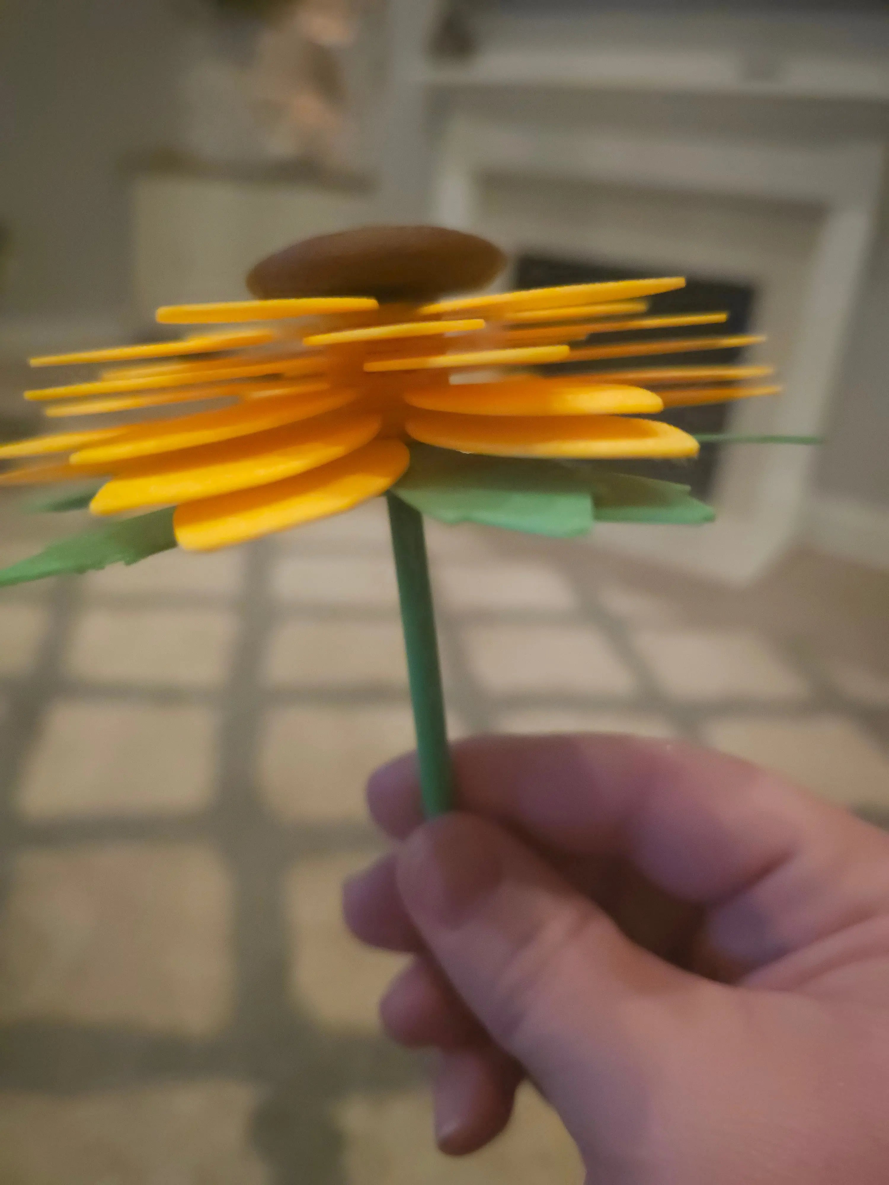 Handmade 3D printed sunflower fidget spinner toy with yellow petals, brown center, and green stem held in a hand - Main Street Collective