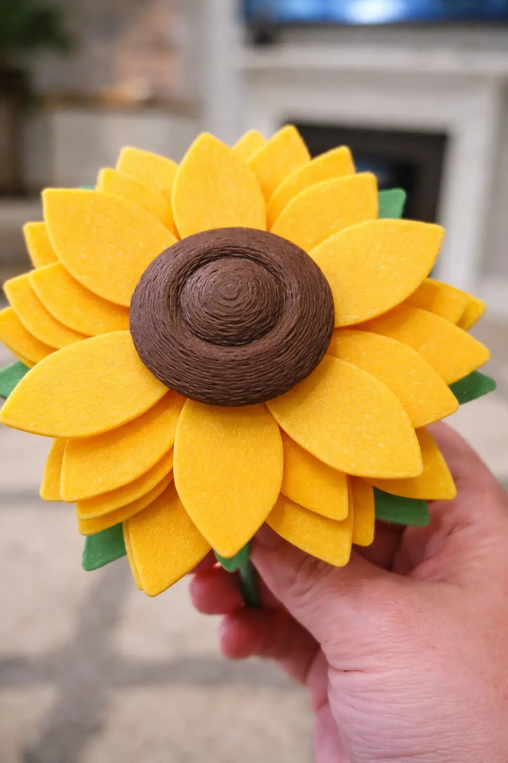 3D printed sunflower fidget spinner with yellow petals and brown center, held in hand.