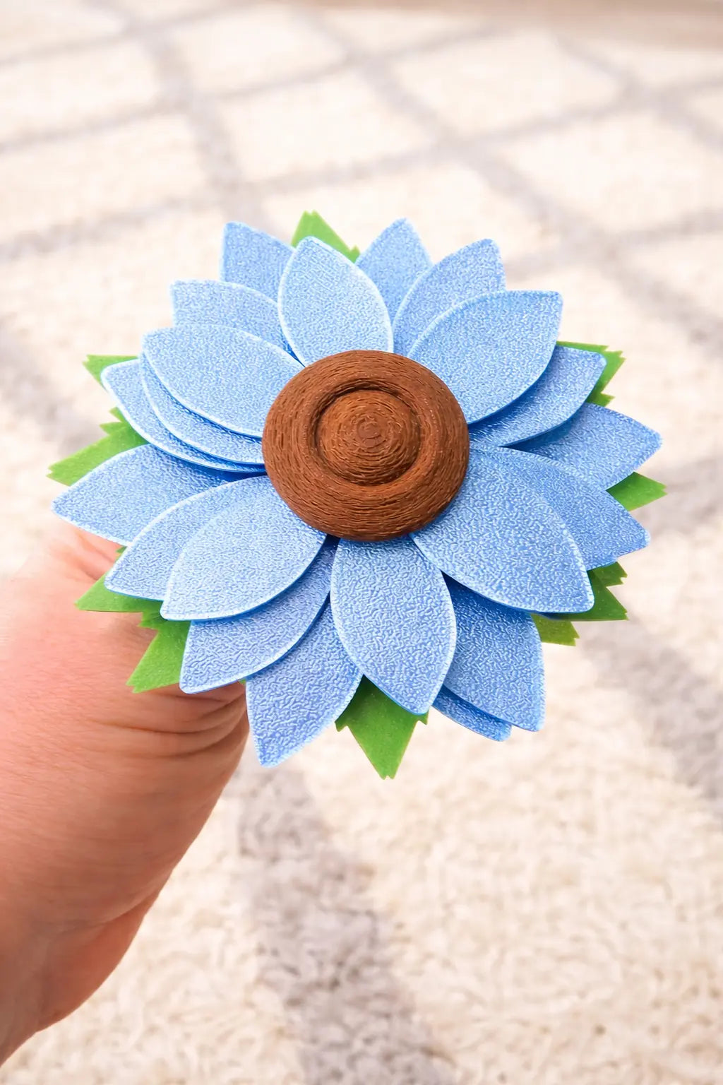 Blue flower fidget spinner with brown center, held in hand. Handmade by Main Street Collective.