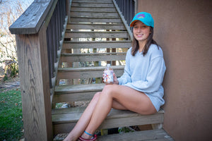 Tuberose Exfoliating Body Wash by Essential Journeys, held by a young woman on stairs