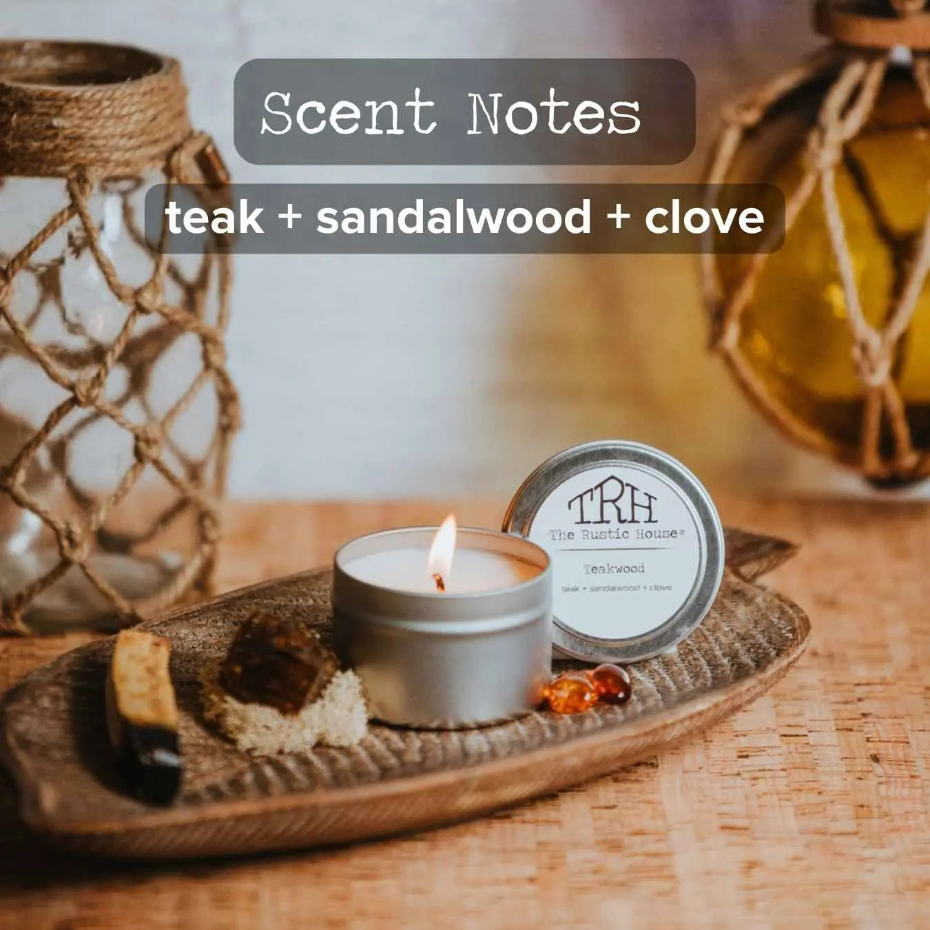 The Rustic House Teakwood scented candle in a silver tin with visible flame.