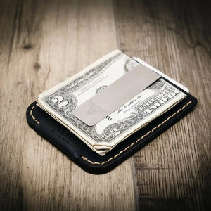 Black leather money clip wallet holding folded dollar bills and a metal clip.