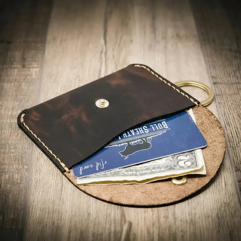 Dark brown leather keychain wallet with blue card and cash.