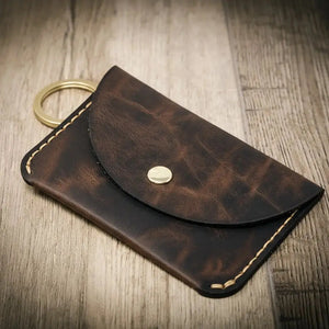 Dark brown leather keychain wallet with brass snap and keyring on wood