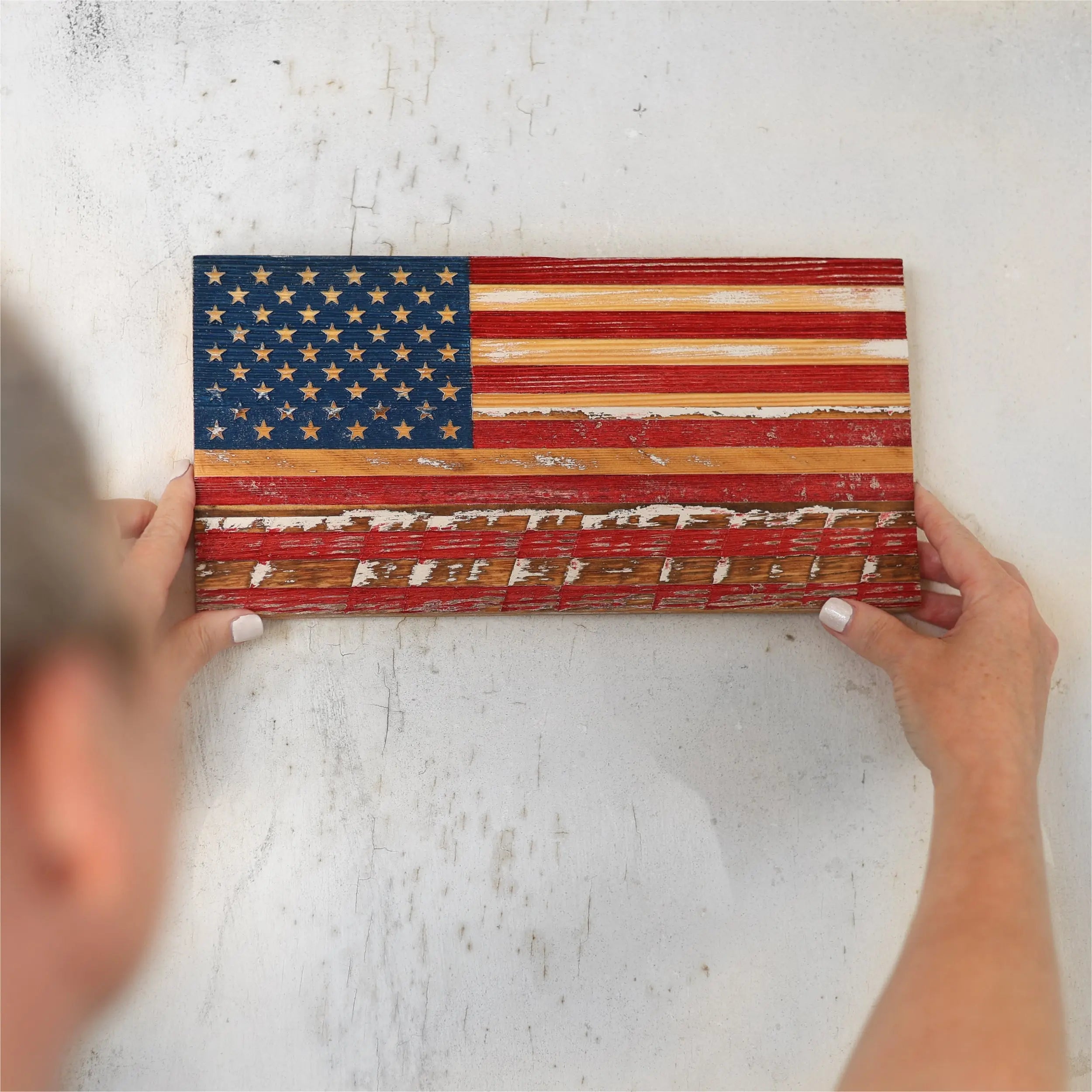 Rustic American flag made from reclaimed pallet wood planks on a textured wall.