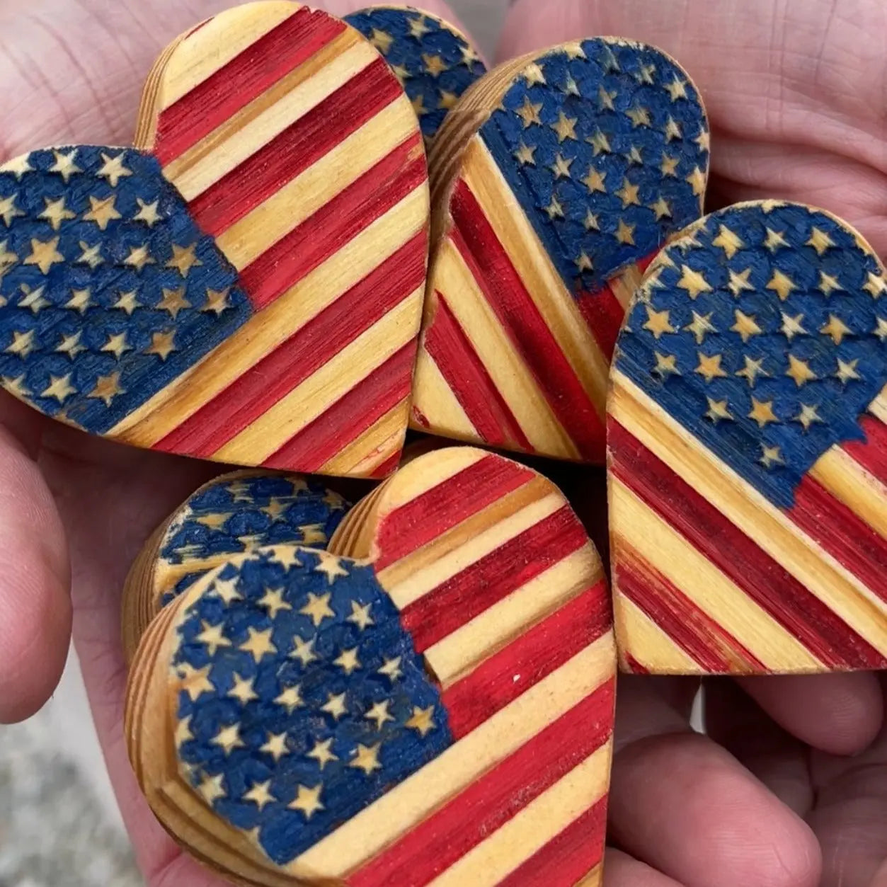 USA wooden hearts with American flag design held in hands.