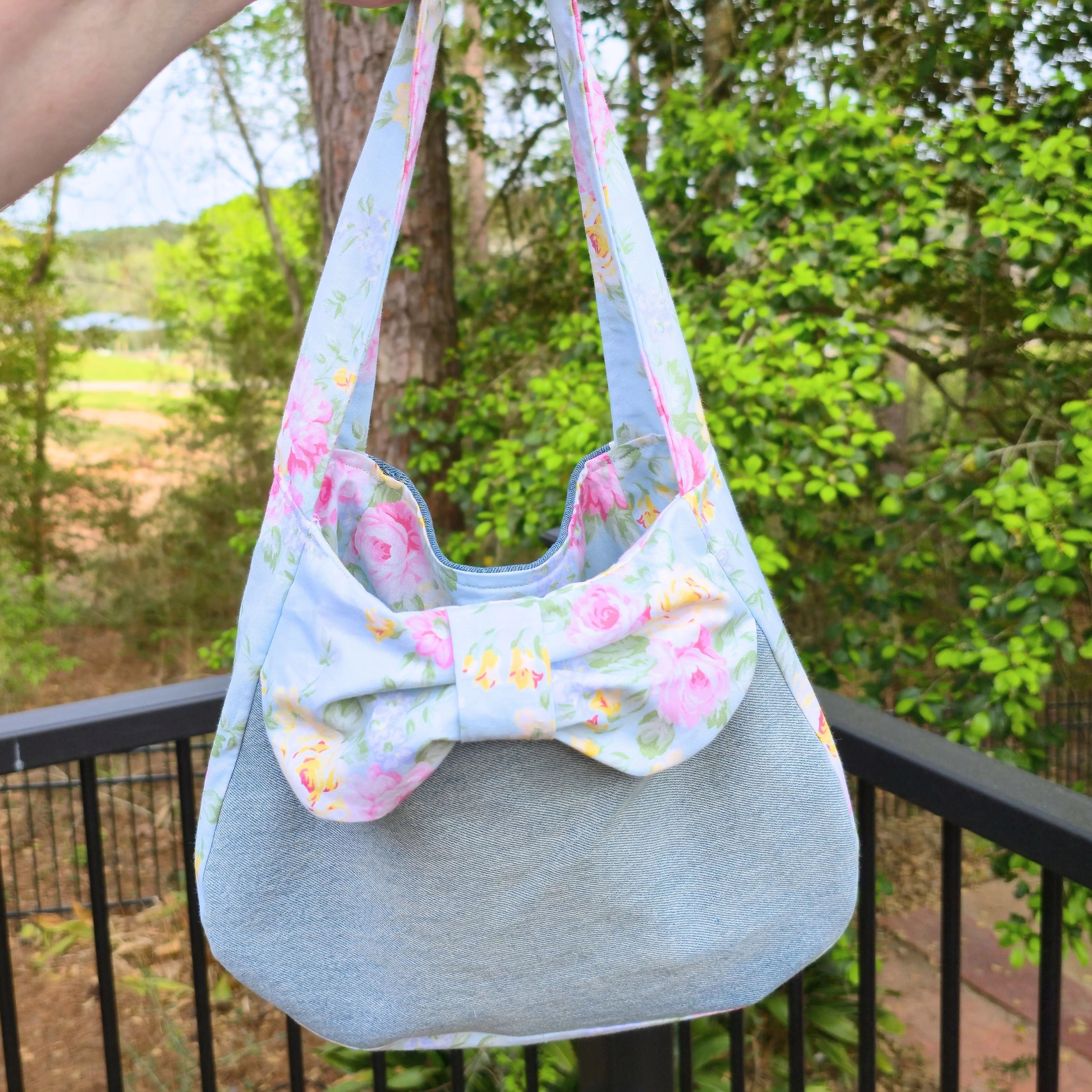 Upcycled denim shoulder bag with a light blue floral bow detail.