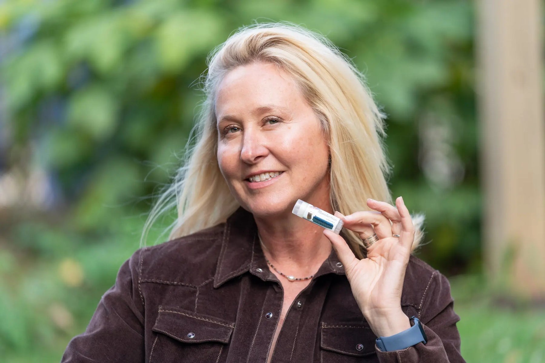 Woman holding a vanilla swirl lip butter tube from The Appalachian Goat.