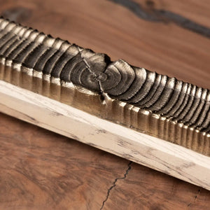Wooden incense holder with bronze casting detail featuring carved rings and light wood base on wood surface.