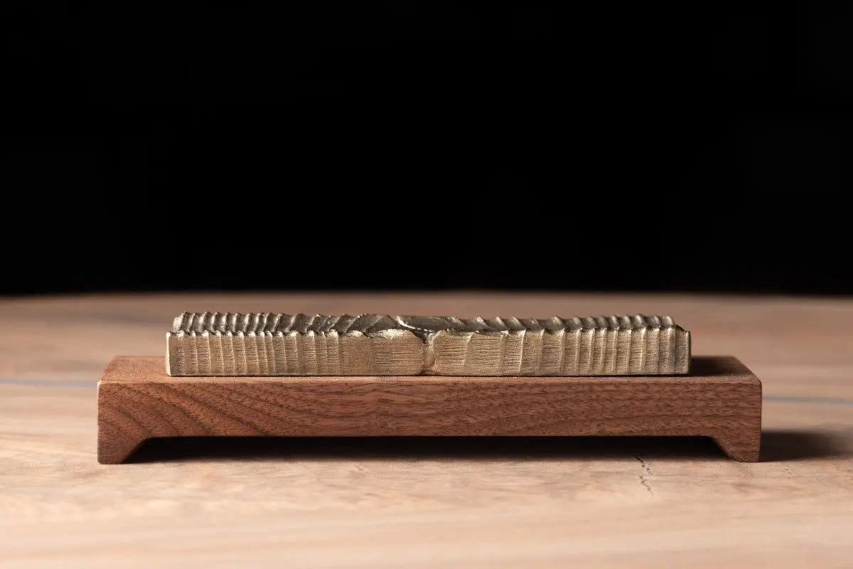 Bronze incense holder with textured design on a wood base. Handcrafted with variations in the bronze casting.