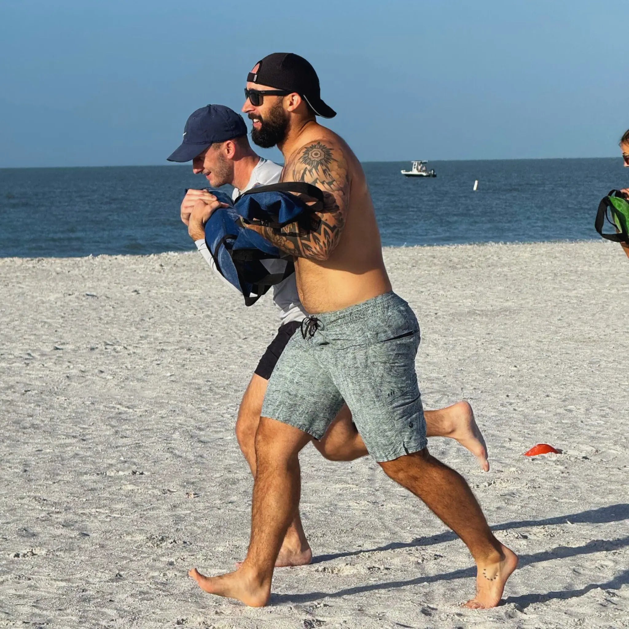 Two men running on a beach with a workout battle bag