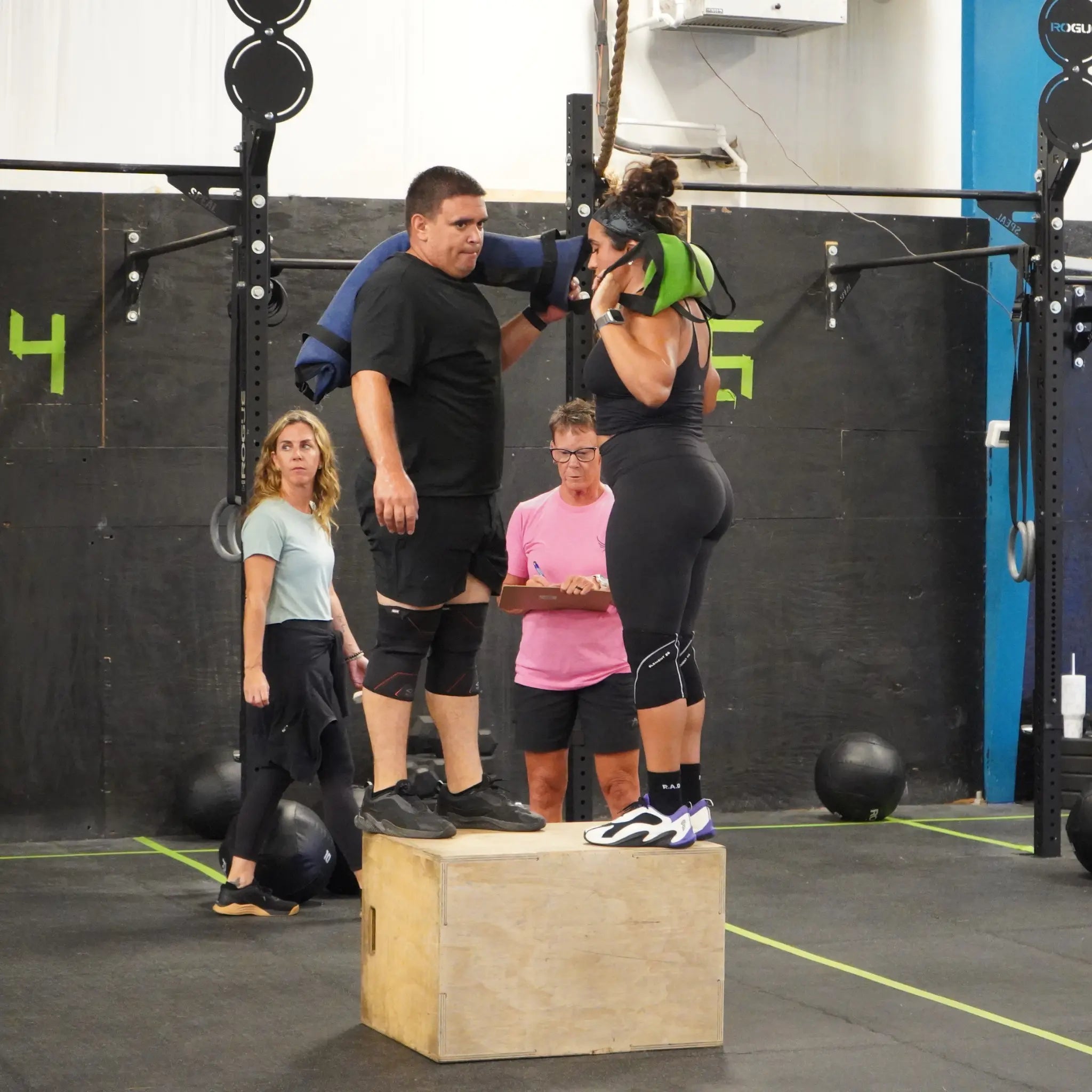Man and woman lifting blue and green workout battle bags in gym
