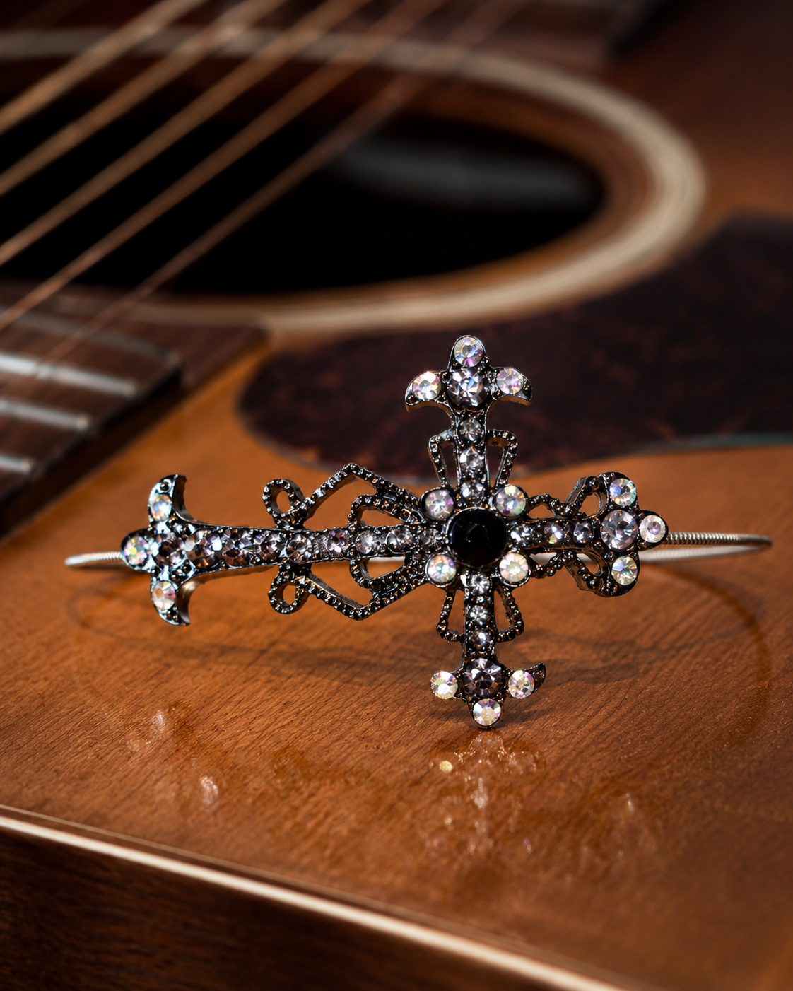 Decorative cross bracelet on a wooden surface with guitar strings in the background