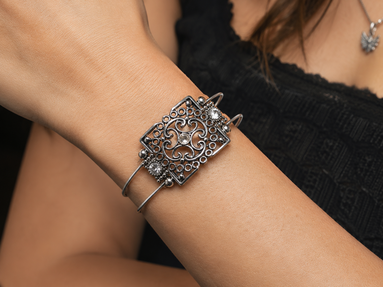 Silver bracelet with intricate design on a wrist against a blurred background