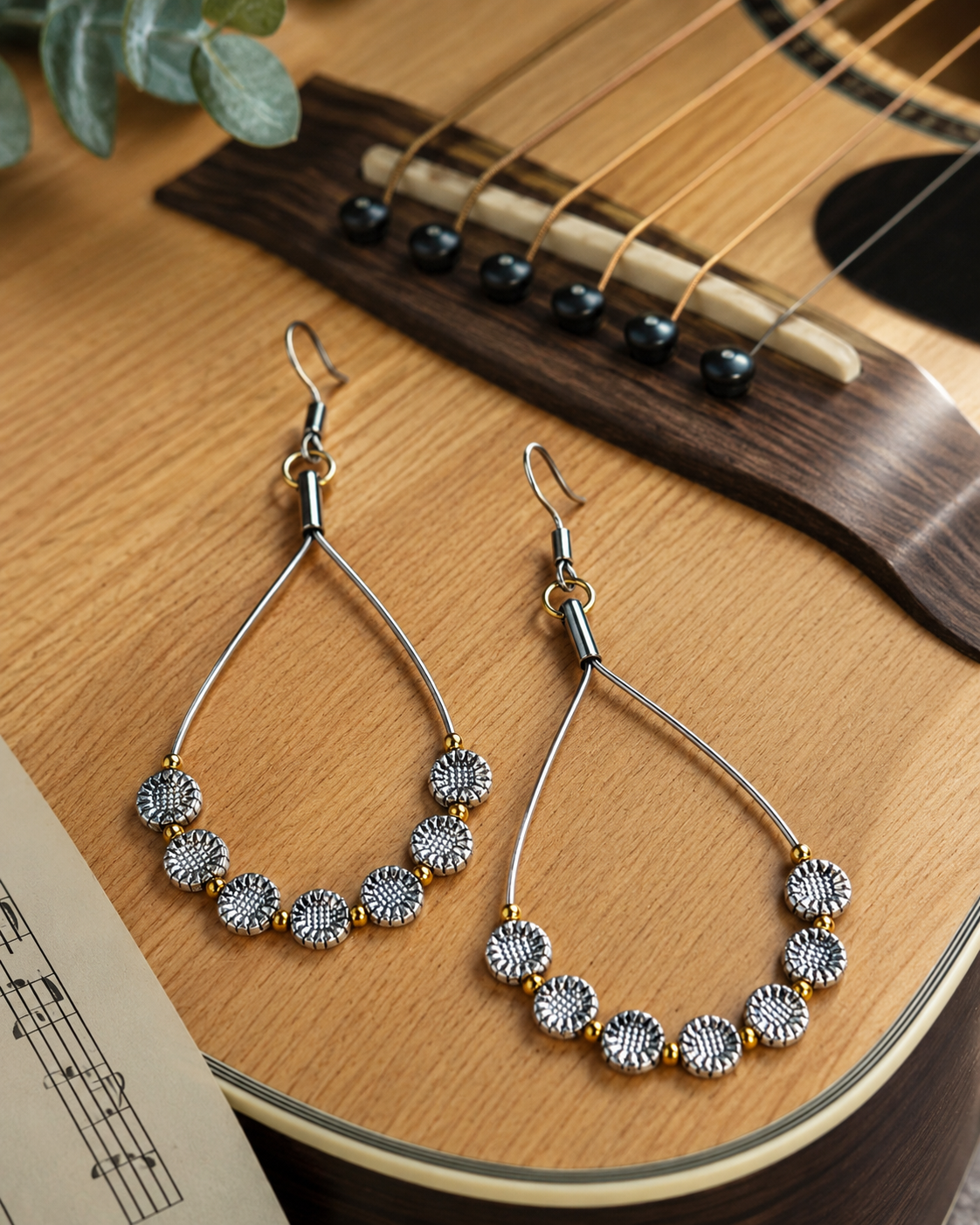 Pair of beaded earrings on a wooden surface with a guitar