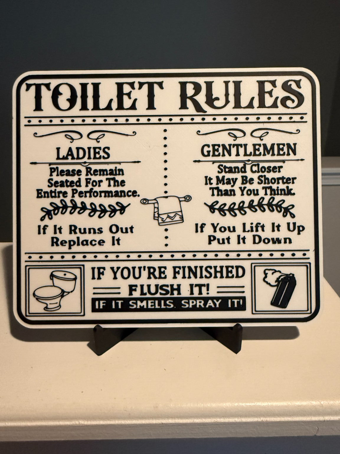 Black and white funny toilet rules bathroom sign on display stand