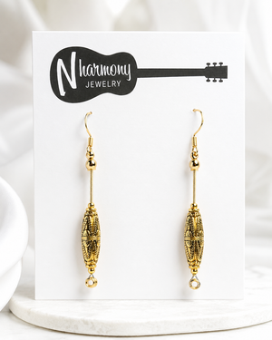 Gold earrings on a 'N' Harmony Jewelry card with a white background