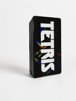 Black mini Tetris style travel puzzle game case on a white table