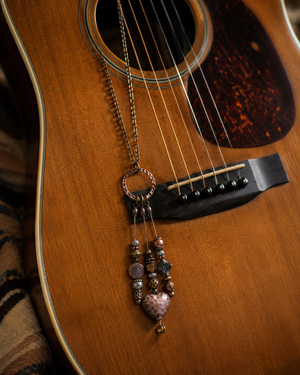 Necklace with beads hanging on an acoustic guitar