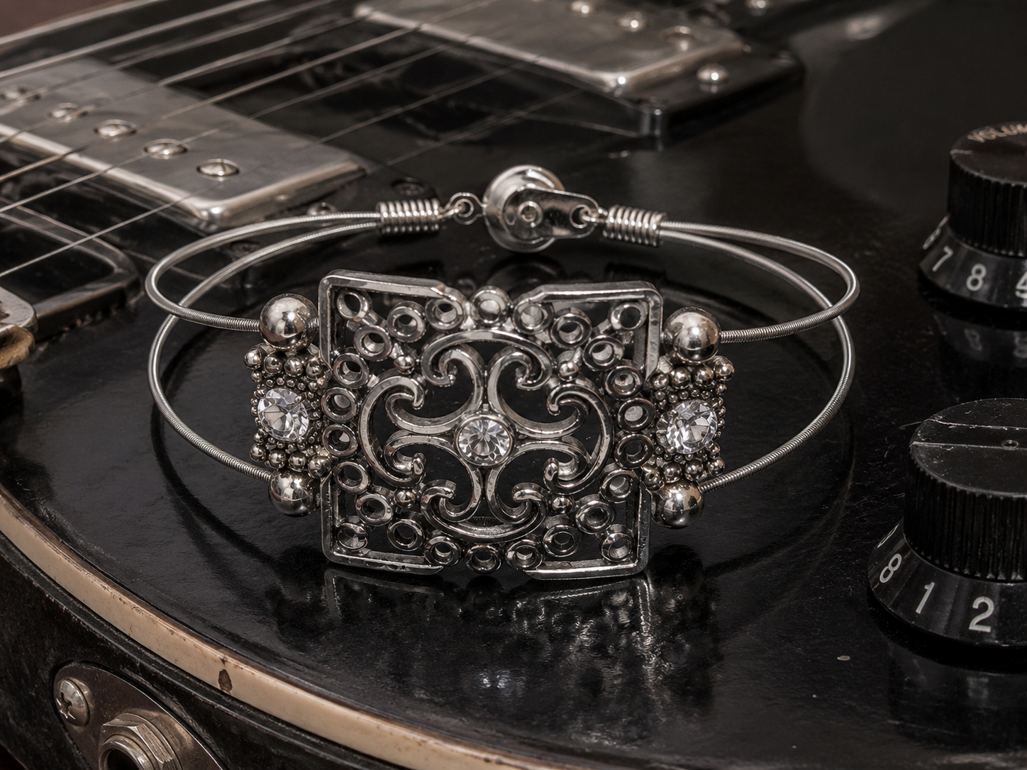 Silver bracelet with intricate design on a guitar