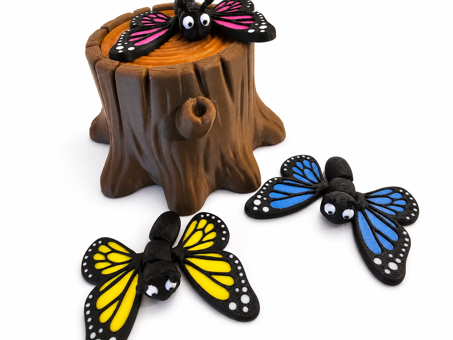 The Tween Space butterfly playset with three colorful 3D printed butterflies and a tree stump on a white background