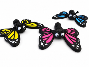 Three colorful 3D printed butterfly figures from The Tween Space with yellow pink and blue wings on a white background
