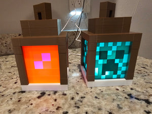 Two handmade block style LED lanterns showing orange window and creeper green designs in daylight