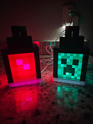 Handmade block style LED lanterns in green and orange styles on a countertop